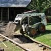 National Park Service equipment operator Jason Willis dumps a load of dirt with his Bobcat into the walkway.